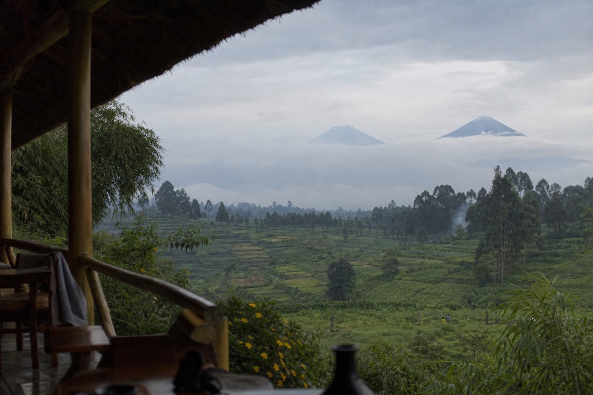 A safari lodge terrace looking out over terraced hills toward the volcanoes